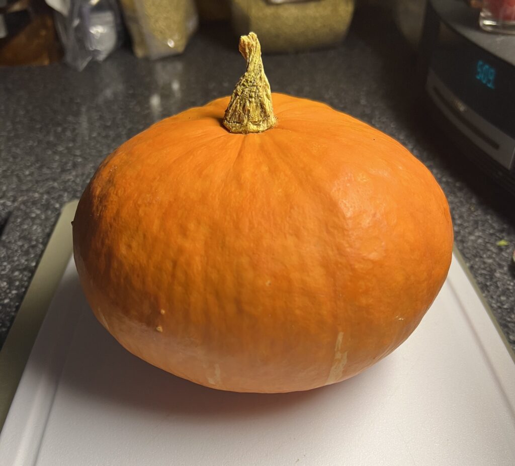 Small cooking pumpkin on white cutting board.